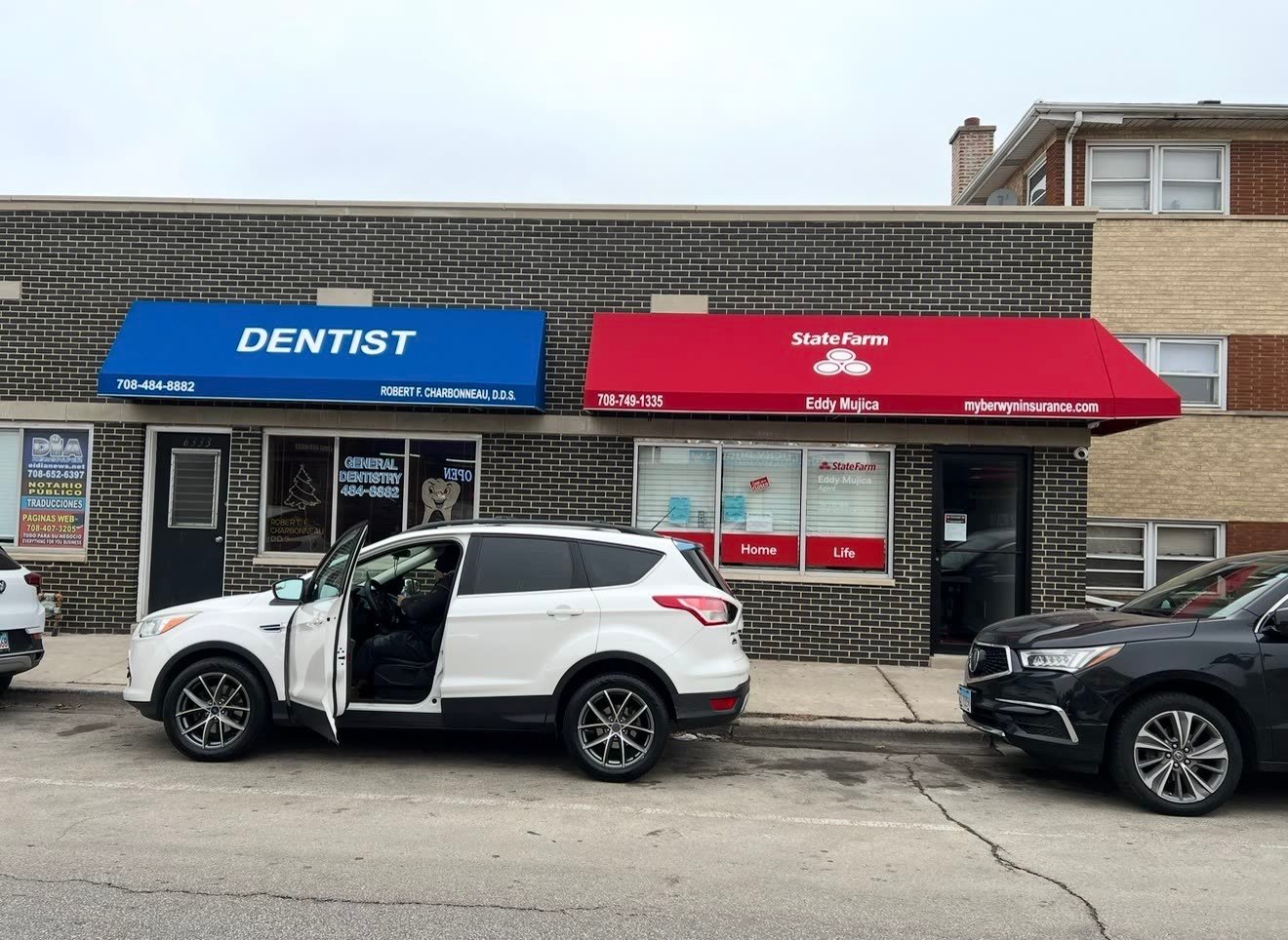 A blue dentist awning and a red insurance office awning on a brick storefront