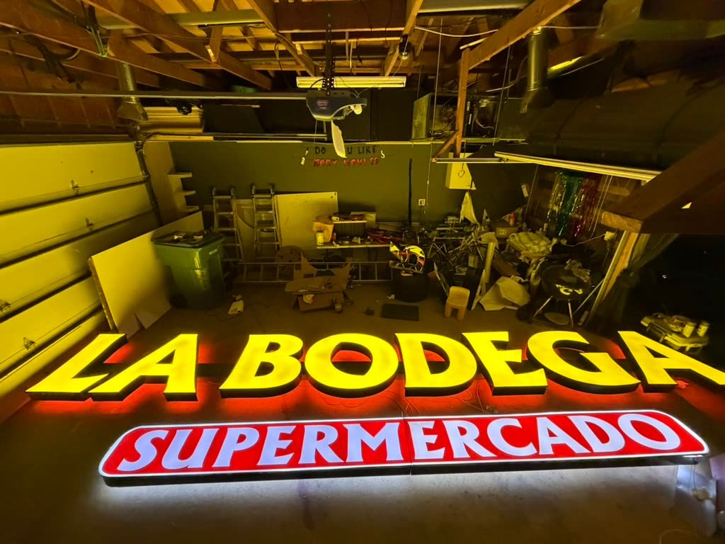 Lit yellow channel letters and a red sign cabinet in the workshop