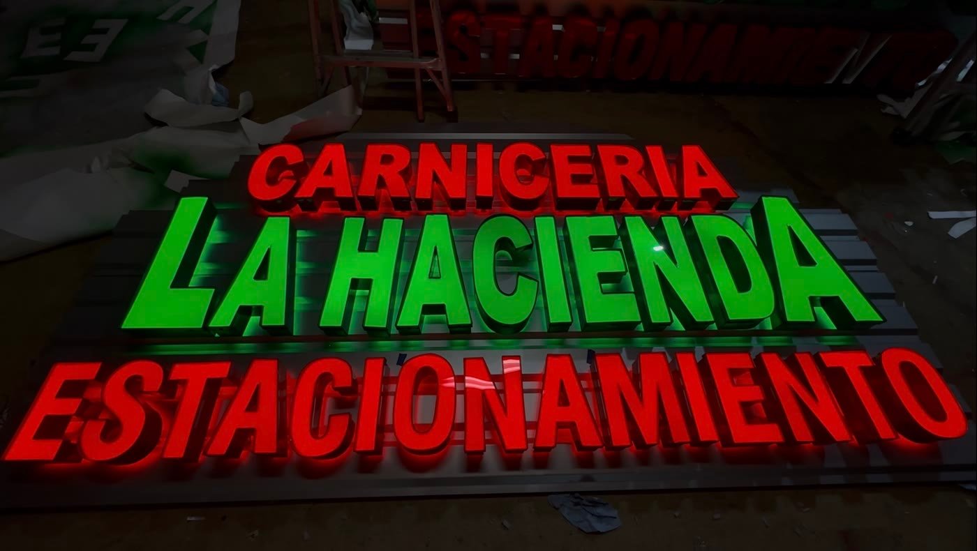 Lit red and green channel letters for Carniceria La Hacienda glowing in the shop before install