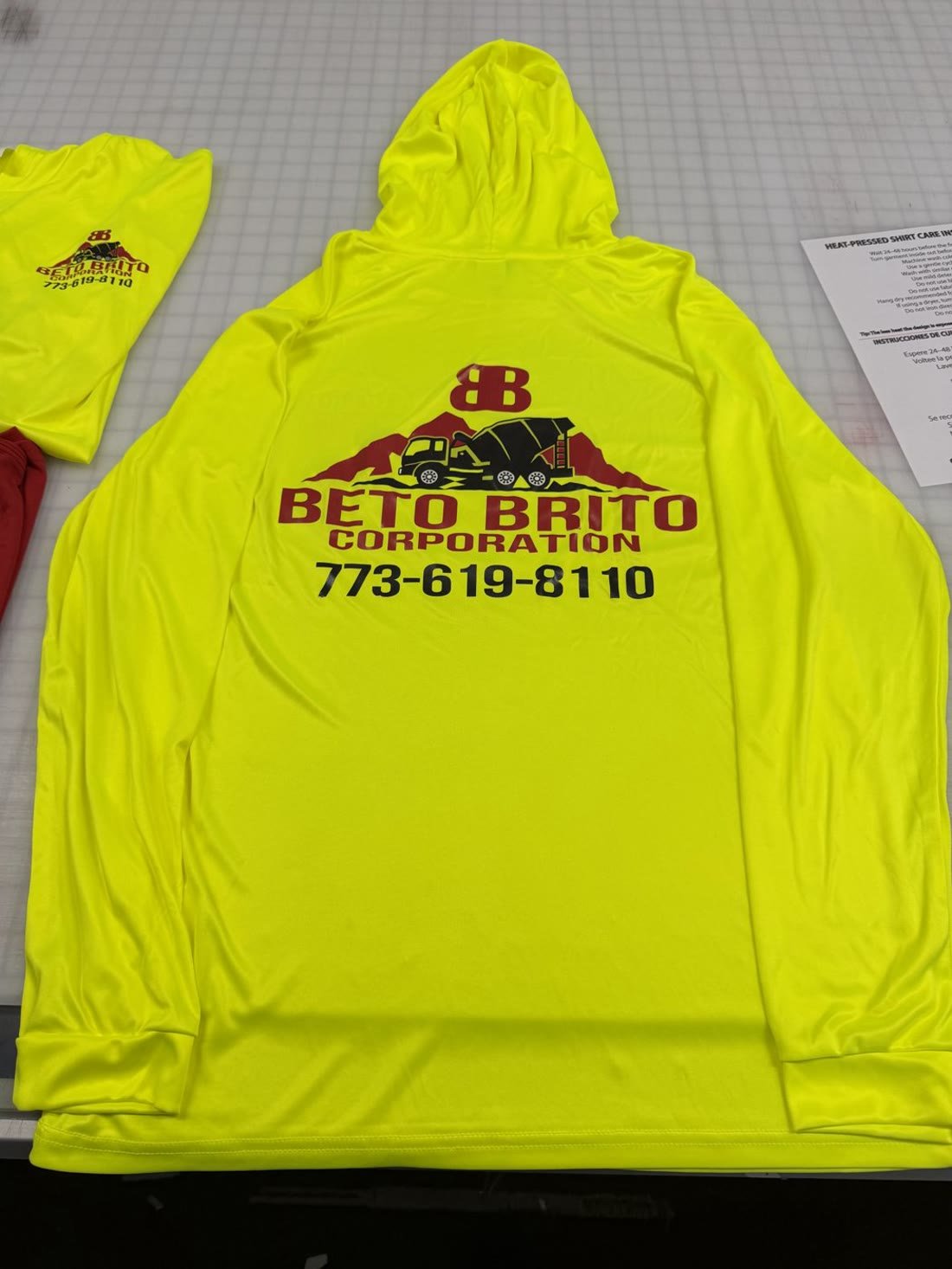 Safety yellow hooded work shirt printed with a concrete company logo and phone number