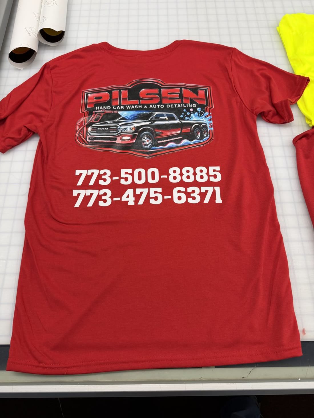 Red t-shirt printed with a full-color car wash logo and two phone numbers